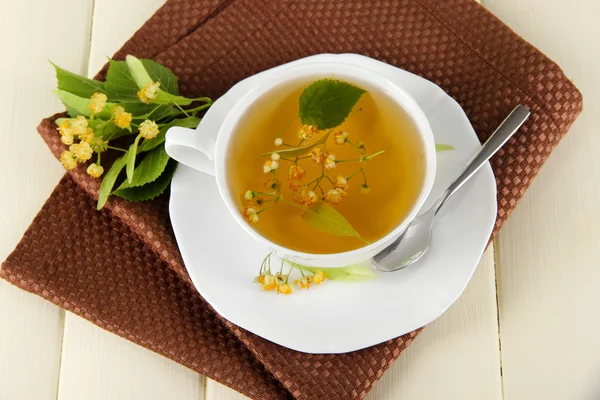 Kopje thee met linden op servet op houten tafel — Stockfoto