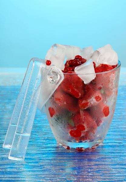 Bagas congeladas em balde de gelo no fundo de cor — Fotografia de Stock