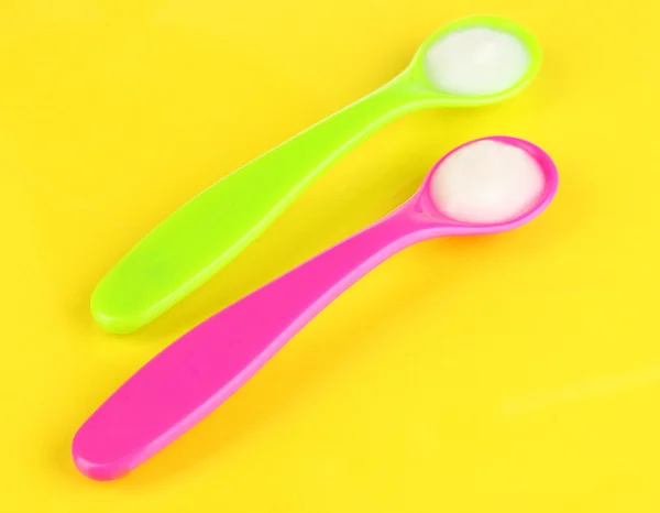 Color spoons for baby food on yellow background — Stock Photo, Image