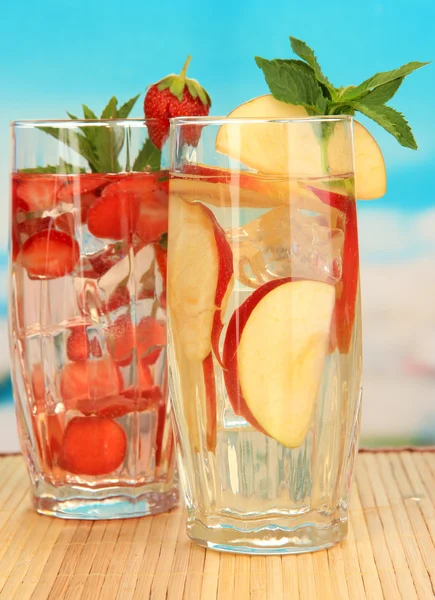 Bicchieri di bevande alla frutta con cubetti di ghiaccio su sfondo blu — Foto Stock
