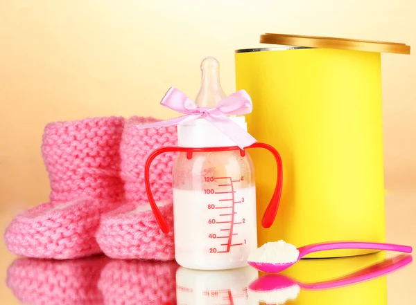 Fles met melk en voedsel voor baby's op beige achtergrond — Stockfoto
