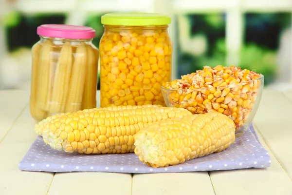 Fresh, canned and dried corn on wooden table, on bright background — Stock Photo, Image