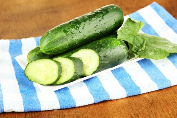 Tasty green cucumbers on color napkin, on wooden background — Stock Photo, Image