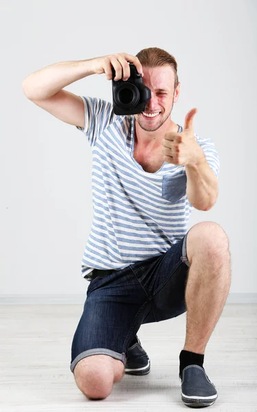 Handsome photographer with camera, on gray background — Stock Photo, Image