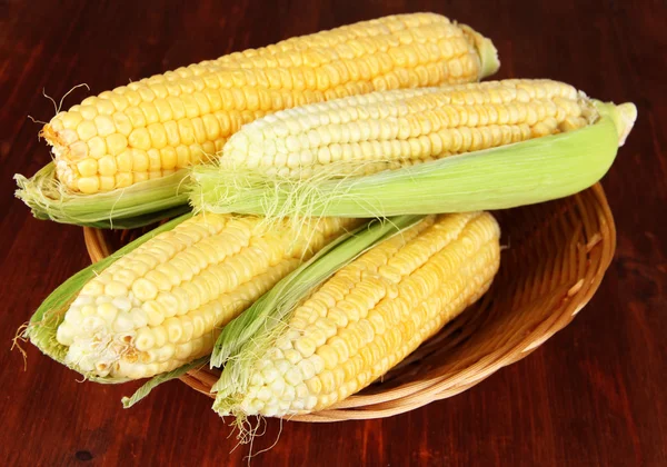 Frisches Maisgemüse im Weidenkorb auf Holztisch — Stockfoto