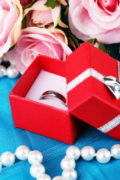 Rosa e anel de noivado em pano azul — Fotografia de Stock
