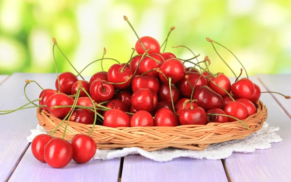 Cherry bessen in rieten mand op houten tafel op lichte achtergrond — Stockfoto