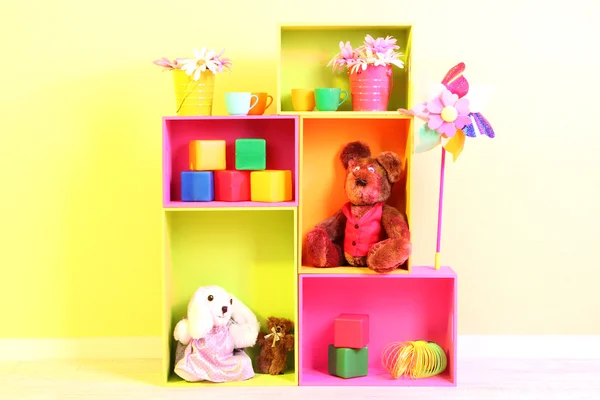 Bright shelves of different colors with toys on wall background — Stock Photo, Image