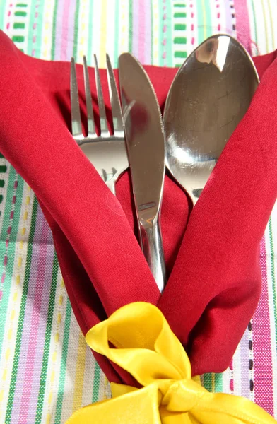 Вилка, ложка, нож в салфетке на ярком фоне — стоковое фото