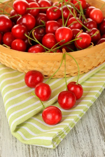 Cherry berries in wicker basket on wooden table close up — Stock Photo, Image