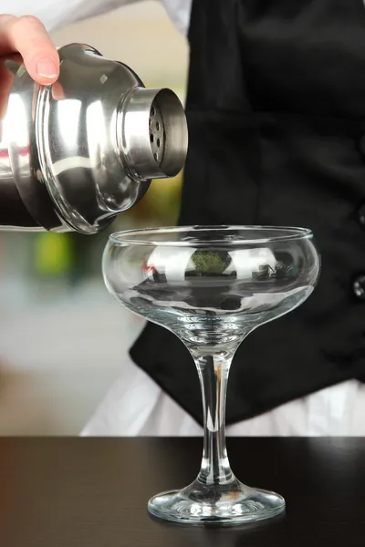 Barmen mano con agitador verter cóctel en el vaso, sobre fondo brillante — Foto de Stock