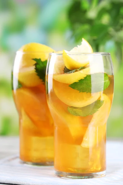 Té helado con limón y menta en la mesa de madera, al aire libre —  Fotos de Stock