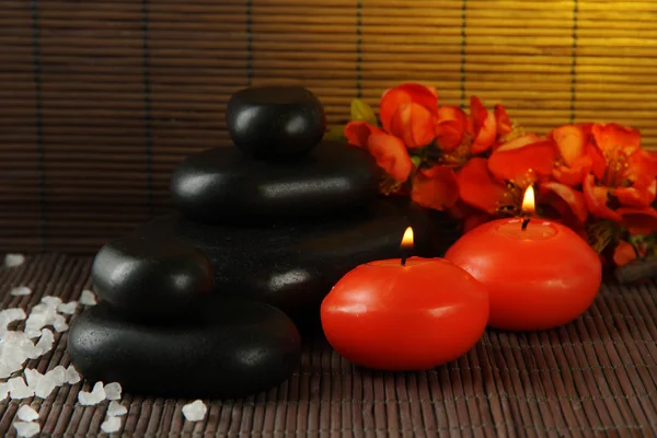 Wellness-Steine mit Blumen und Kerzen auf Bambus-Hintergrund — Stockfoto
