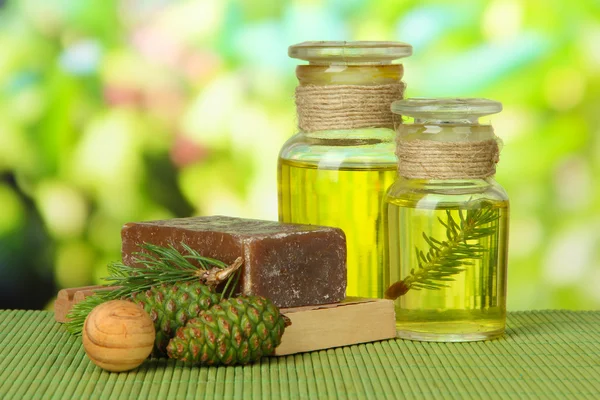 Ručně vyráběné mýdlo a lahve fir tree oil na bambusové rohoži — Stock fotografie