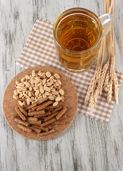 Beer in glass crunches, and nuts on napkin on wooden table — Stock Photo, Image