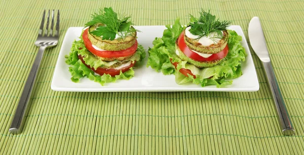 Tasty moelle rôtie et tranches de tomate avec feuilles de salade, sur tapis de bambou, sur fond de bois — Photo