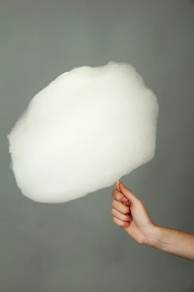 Hand holding stick with cotton candy, on color background — Stock Photo, Image