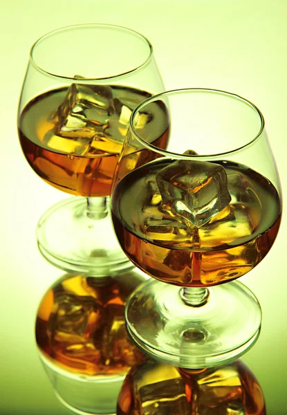 Brandy glasses with ice on green background — Stock Photo, Image