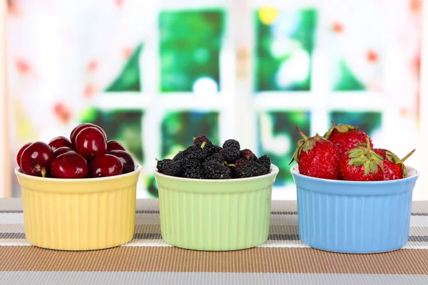 Rijp moerbeien met cherry en aardbeien in kommen op tafel op kamer — Stockfoto