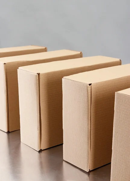 Cardboard boxes on conveyor belt, on grey background — Stock Photo, Image