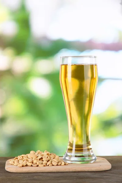 Birra in vetro e noci sul tavolo sullo sfondo della natura — Foto Stock