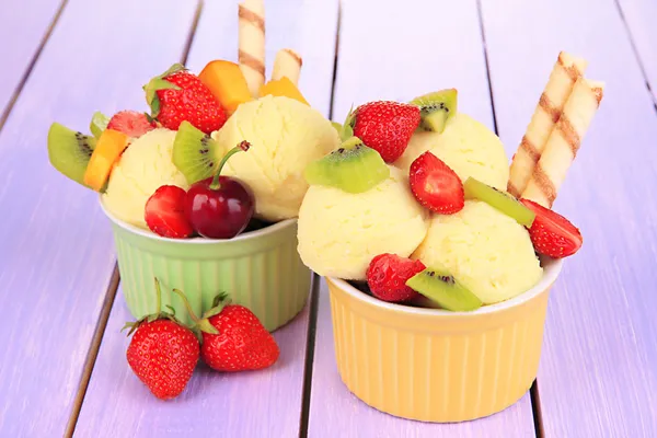 Delicioso helado con frutas y bayas en un tazón sobre una mesa de madera —  Fotos de Stock