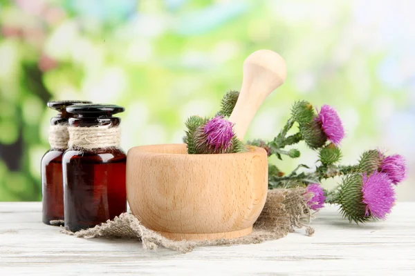 Botellas de medicina y mortero con flores de cardo sobre fondo natural —  Fotos de Stock