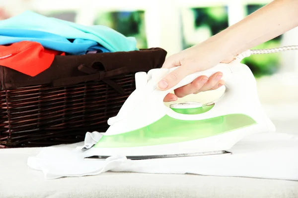 Woman's hand ironing clothes, on bright background — Stock Photo, Image