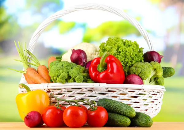Świeże warzywa w biały wiklinowy koszyk na jasnym tle — Zdjęcie stockowe