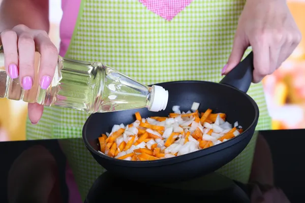 Manos cocinando cebolla frita con zanahoria en sartén en la cocina — Foto de Stock