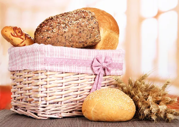 Baked bread in wicker basket on window background — Stock Photo, Image