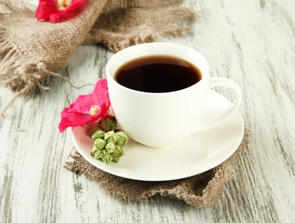 Kopje koffie en roze kaasjeskruid bloemen op houten achtergrond — Stockfoto