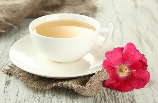 Taza de té y flor de malva rosa sobre fondo de madera — Foto de Stock