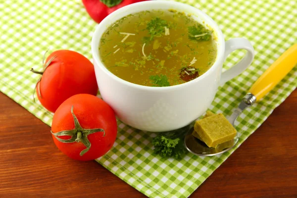 Cup of soup with bouillon cubes on wooden background — Stock Photo, Image