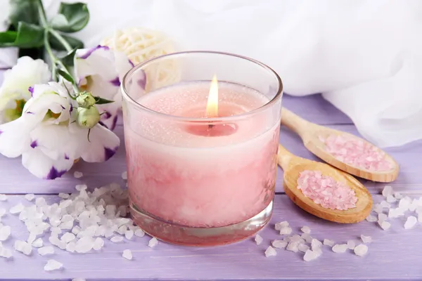 Beautiful pink candle with flowers on purple wooden background — Stock Photo, Image