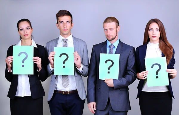 Business team standing in row with question mark on grey background — Stock Photo, Image