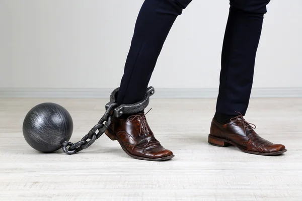 Obchodní pracovník s míčem a řetězec připojený k patě — Stock fotografie