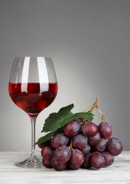灰色の背景にテーブル上にワインのガラスと熟した美味しいぶどう — ストック写真