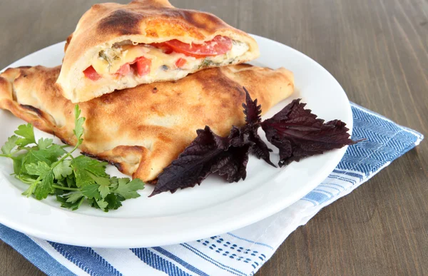 Pizza calzone on plate on napkin on wooden table — Stock Photo, Image