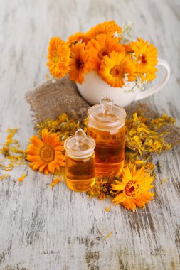 ilaç şişeleri ve ahşap zemin üzerine calendula çiçekler