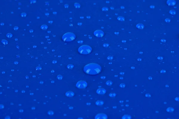 Gocce d'acqua su sfondo di plastica blu — Foto Stock