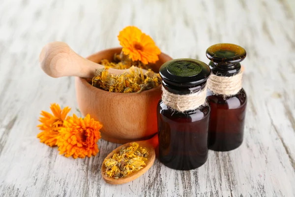 Medizinflaschen und Ringelblumen auf Holzgrund — Stockfoto
