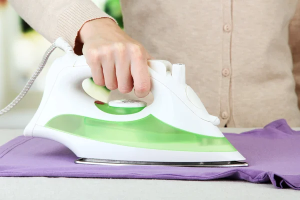 Woman's hand ironing clothes, on bright background — Stock Photo, Image