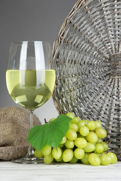 Läckra mogna druvor med glas vin på bordet på grå bakgrund — Stockfoto