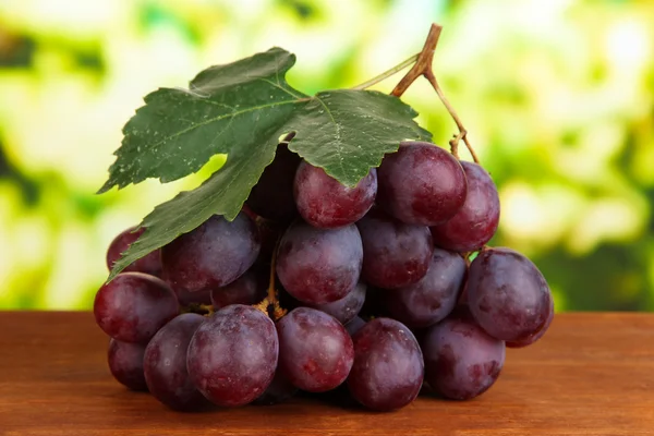 Ripe delicious grapes on table on bright background — Stock Photo, Image