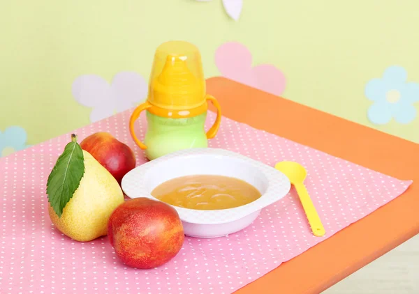 Tasty baby fruit puree and baby bottle on table in room — Stock Photo, Image