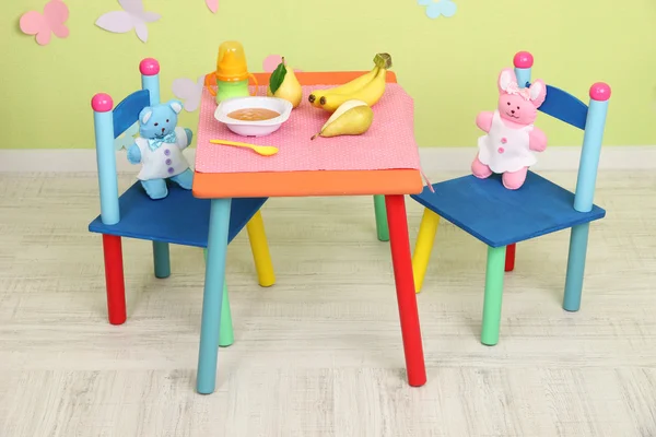 Ízletes baba gyümölcs püré és cumisüveg asztalon a szobában — Stock Fotó