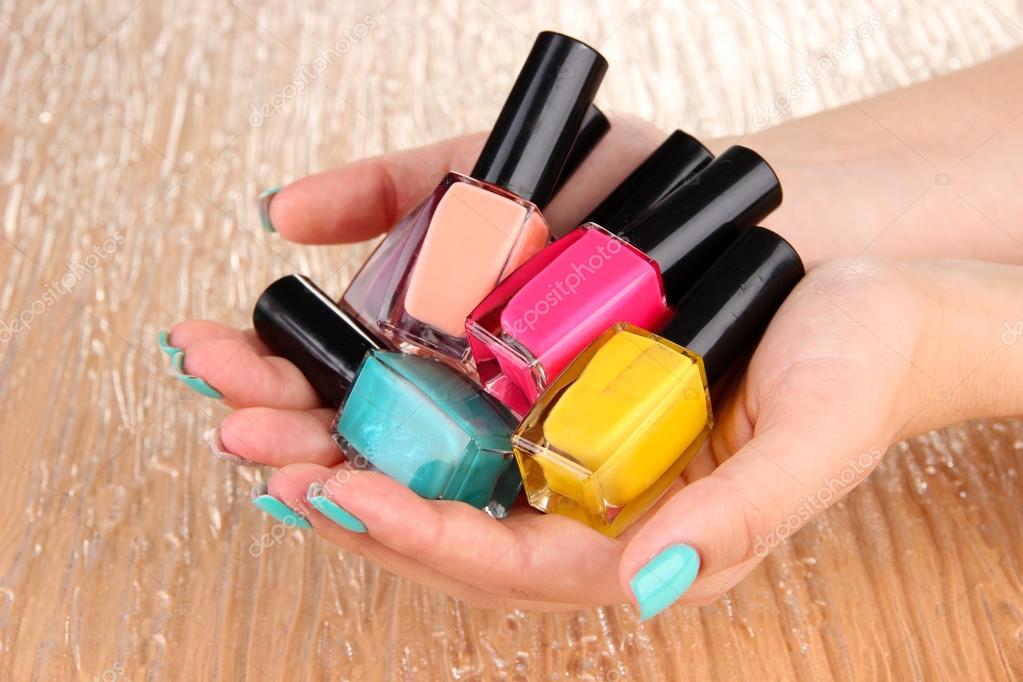 Beautiful woman hands with blue manicure and several bottles with nail  polish, on color background Stock Photo by ©belchonock 27544293