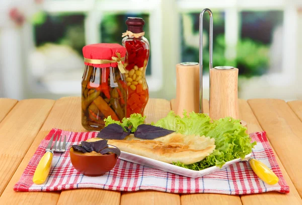 Leckere Chebureks mit frischen Kräutern auf Teller, Holztisch, auf hellem Hintergrund — Stockfoto