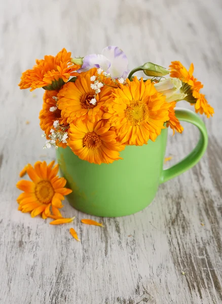 Calendula flowers in cup on wooden background — Stock Photo, Image